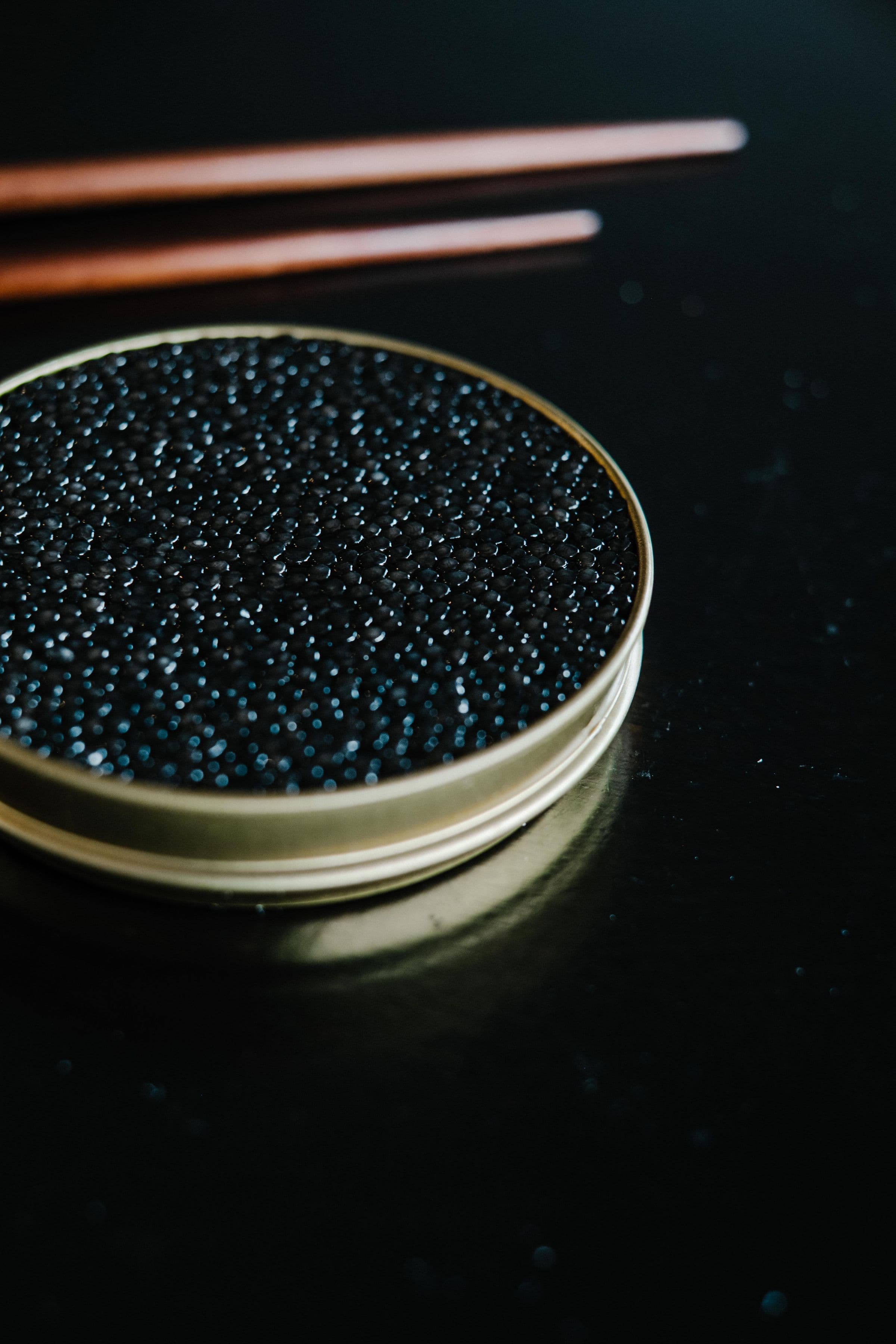 Lata de caviar negro sobre superficie oscura, composición mínima y elegante